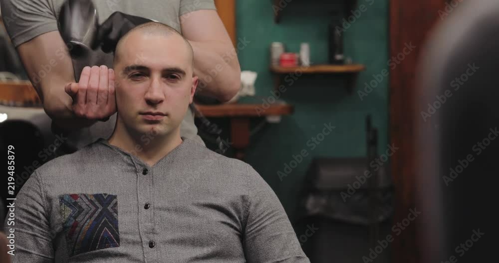 Master cuts hair and beard of men in the barbershop, hairdresser makes hairstyle for a young man Master cuts hair and beard of men in the barbershop, hairdresser makes hairstyle for a young man