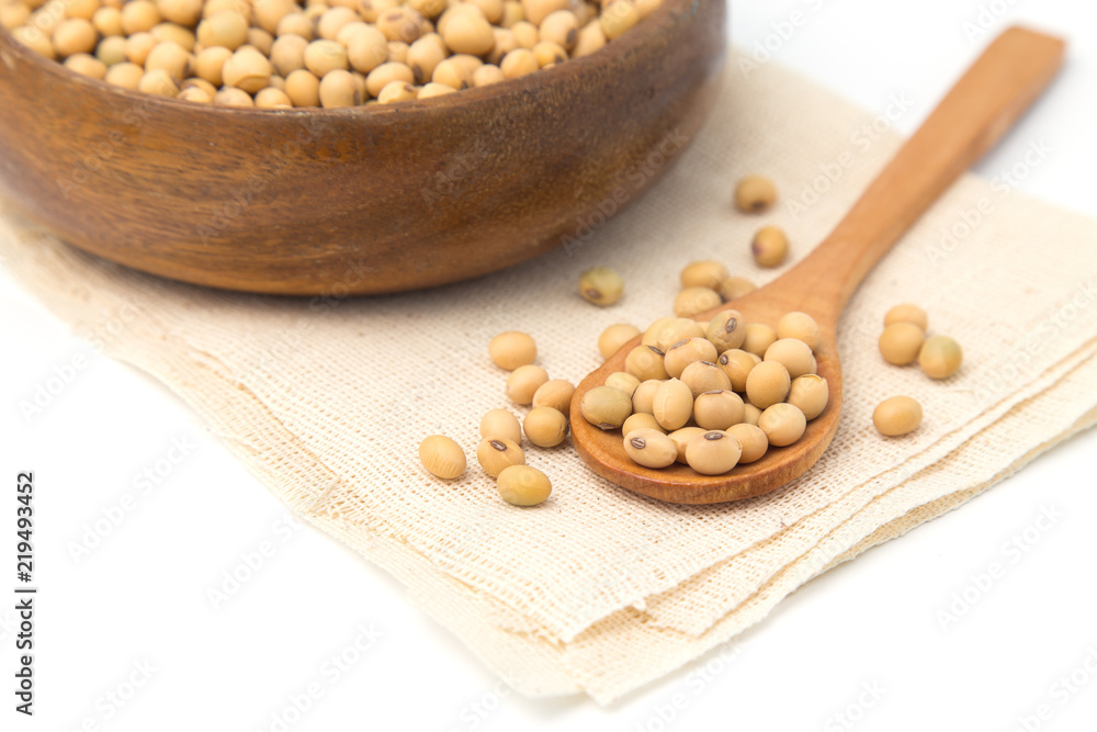 Soybeans in wooden bowl and spoon putting on linen and white background. Soybeans in wooden bowl and spoon putting on linen and white background.