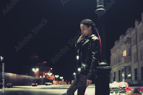 Prostitute with cigarette working on the night street. model informal appearance holding a cigarette in his hands. bad habit, harmful habit, pernicious habit, unhealthy habit. photo