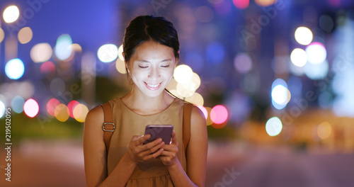 Canvas Print Woman use of mobile phone with blur city in the evening