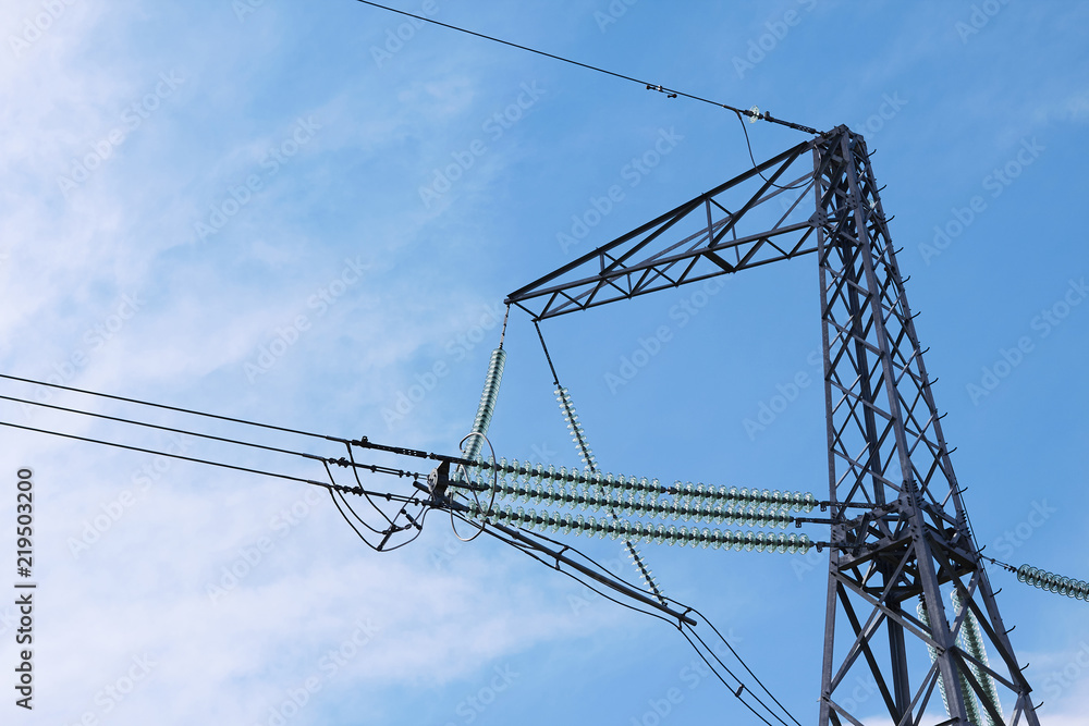 electricity transmission pylon silhouetted against blue sky