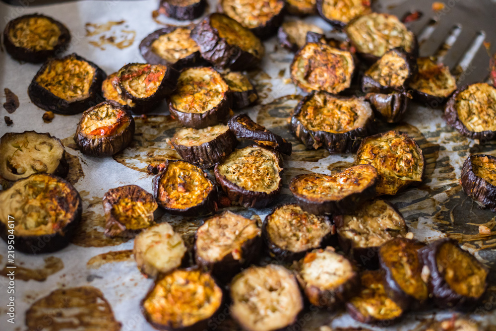 Roasted, grilled eggplants round slices with oregano herbs, spices baked on parchment paper in oven. Vegan vegetarian healthy lunch or dietary dinner. Roasted, grilled eggplants round slices with oregano herbs, spices baked on parchment paper in oven. Vegan vegetarian healthy lunch or dietary dinner.