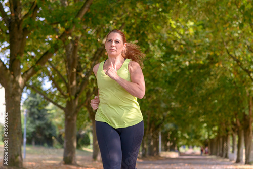 Fit middle-aged woman jogging through a park