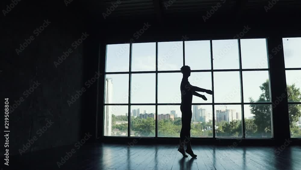 silhouette of a ballet dancer on the background of a large window. the dancer turns on tiptoe and gracefully moves silhouette of a ballet dancer on the background of a large window. the dancer turns on tiptoe and gracefully moves