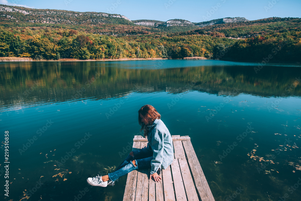 Fototapeta premium Person sitting on peer by the lake