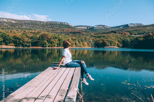 Person sitting on peer by the lake