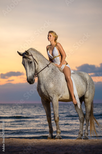 beautiful woman sitting on a horse on the beach