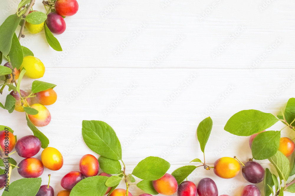 frame with fresh plums with leaves on white rustic wooden table. The concept of autumn harvest. frame with fresh plums with leaves on white rustic wooden table. The concept of autumn harvest.