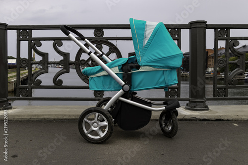 blue baby stroller stands alone on the bridge