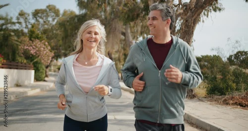 Happy mature couple jogging together on sunny day in spring