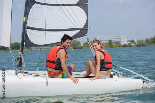young couple steering a catamaran