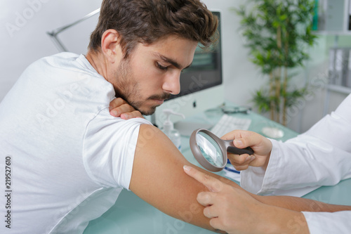 close-up of doctors hands checking mans moles