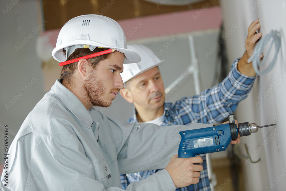 apprentice is drilling holes at construction site apprentice is drilling holes at construction site