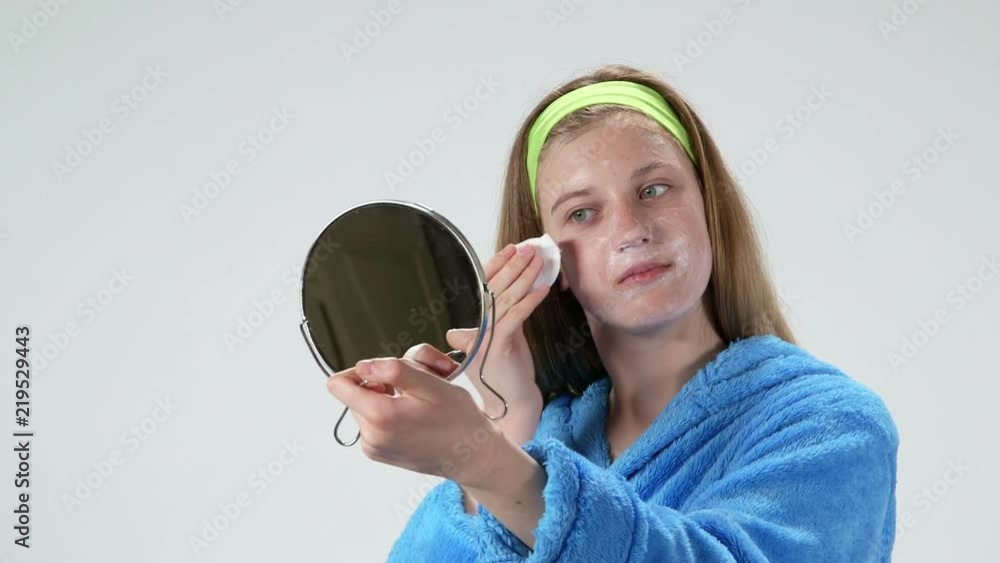Teenage girl applying facial cleansing mask after bath. Beauty treatments for teens. Teenage girl applying facial cleansing mask after bath. Beauty treatments for teens.