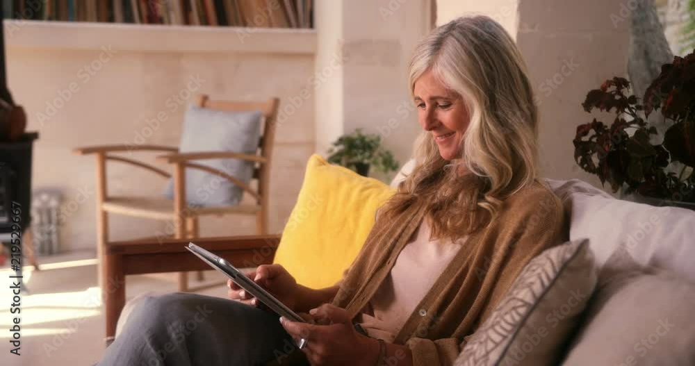 Fashionable mature woman having fun using tablet at home Fashionable mature woman having fun using tablet at home