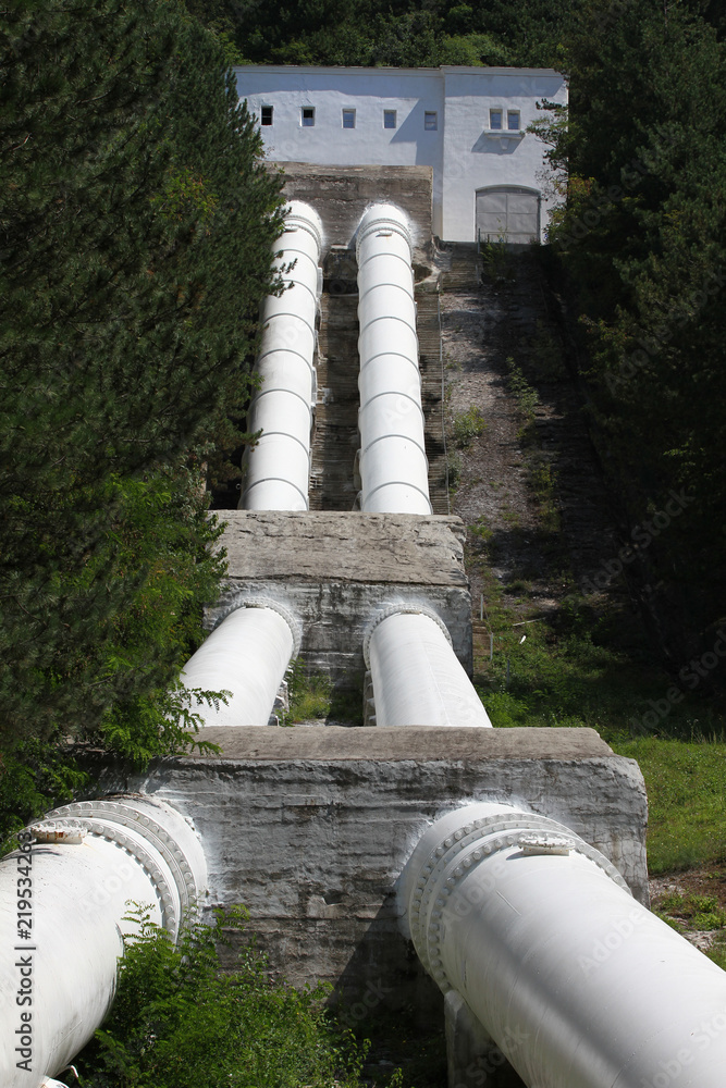 Fototapeta premium Pipes of a hydroelectric power station in nature. Lake Iskar hydroelectric dam. Kokalyane Hydroelectric Power Plant in Pancharevo, Sofia. Tubes for hydroelectric power plant. Man and nature. Pollution