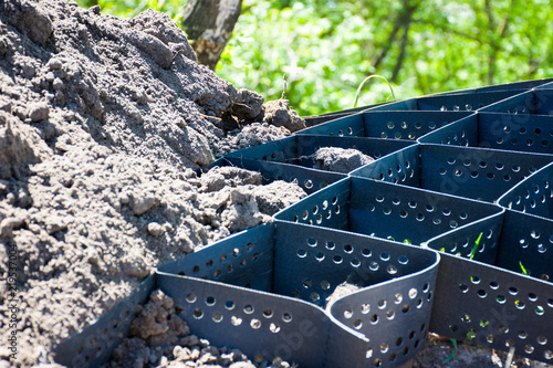 Scene of technology of strengthening the slope of a hill, mountain or ravine using plastic geogrid. Photos with an empty and already covered with soil geogrid closeup on a background with greenery