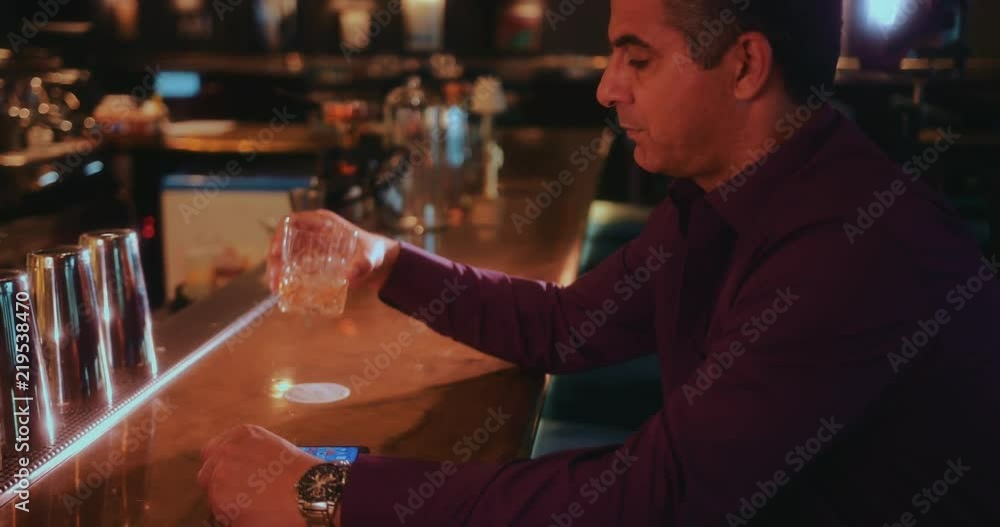 Mature man waiting at bar and looking at watch Mature man waiting at bar and looking at watch