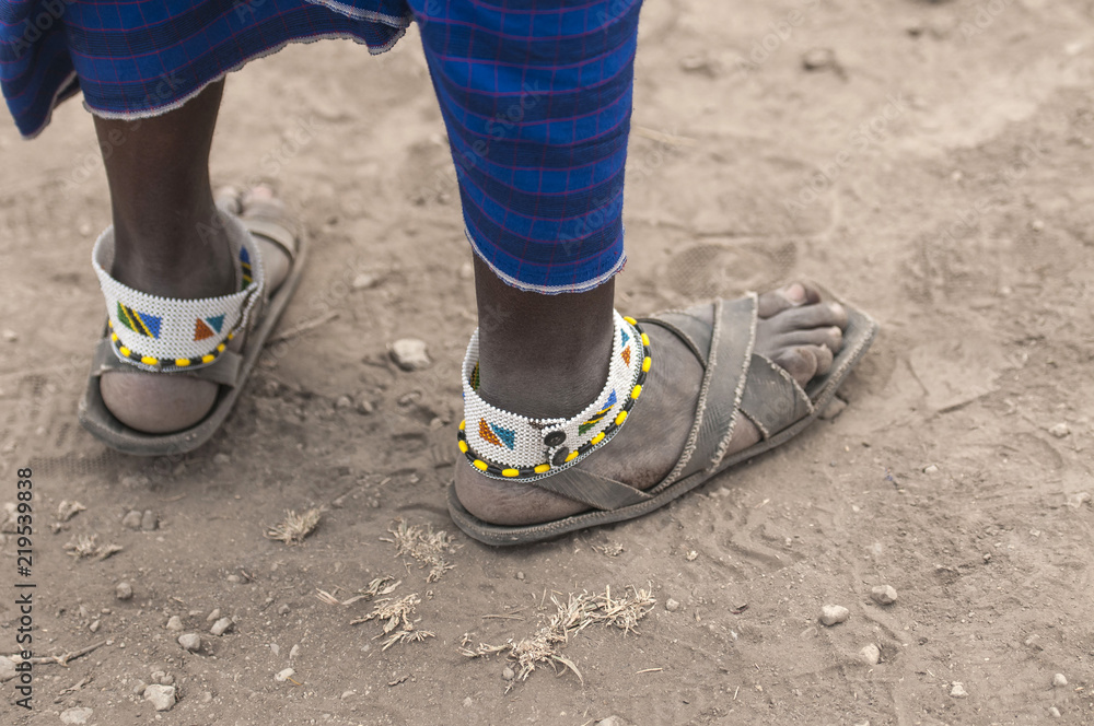 Traditional tribal bead work worn around ankle by masai man, also wearing very old and worn sandals. Tanangire National Park, Tanzania