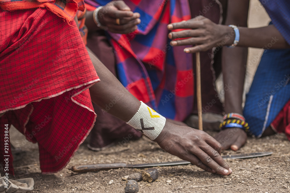 Fototapeta premium Traditional tribal bead work worn around wrist by Masai man as he lights a fire using traditional method of stone and stick. Tanangire National Park, Tanzania