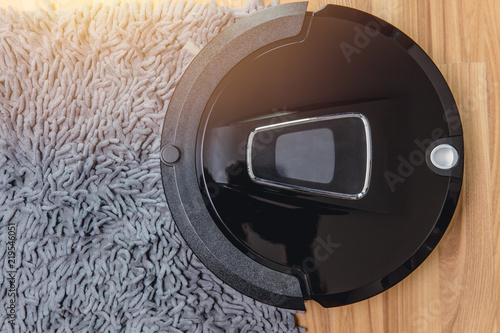 Automate Robot vacuum cleaner on laminate wood floor with carpet cleaning machine. photo