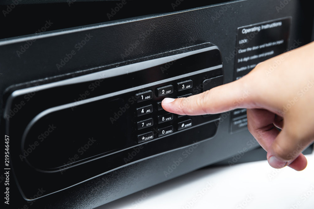 Digital safety safe box in hotel room service with hand using finger at password key pad Digital safety safe box in hotel room service with hand using finger at password key pad