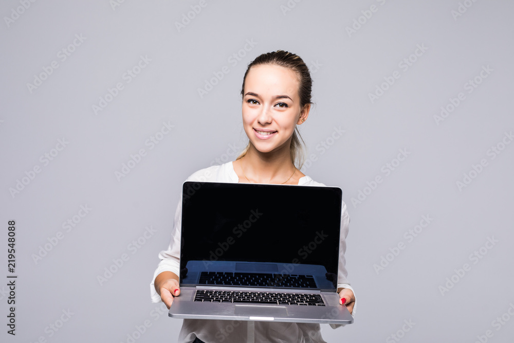 Happy business woman showing blank laptop screen over gray background Looking at camera Happy business woman showing blank laptop screen over gray background Looking at camera