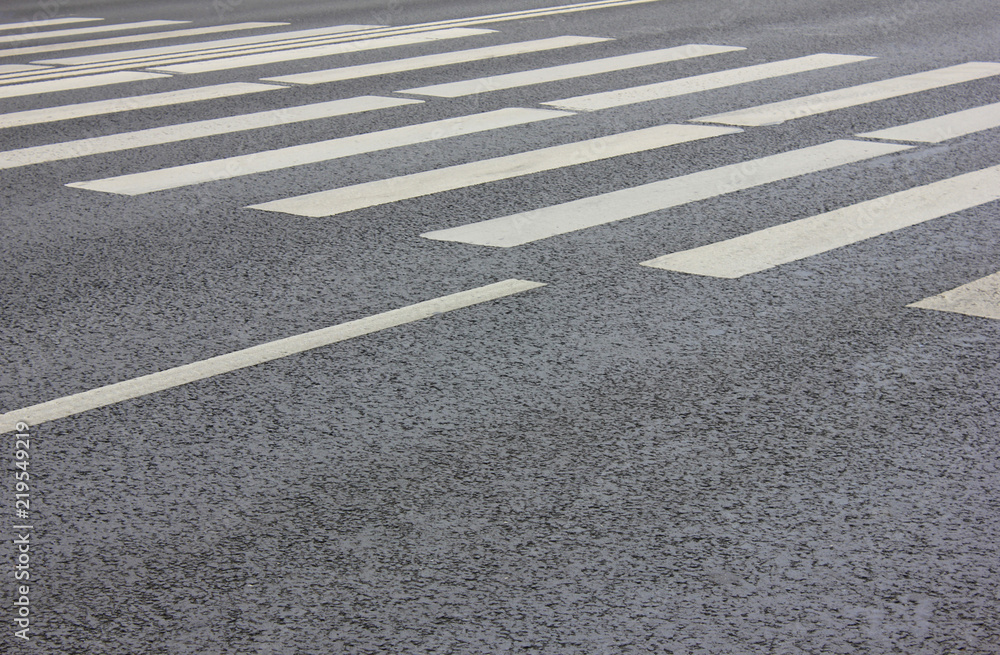 Crosswalk on City Street with Parallel Painted White Zebra Lines and Empty Asphalt Road Background. Pedestrian Cross Walk View with Traces from Wheel Tires at Crossing Point on City Street