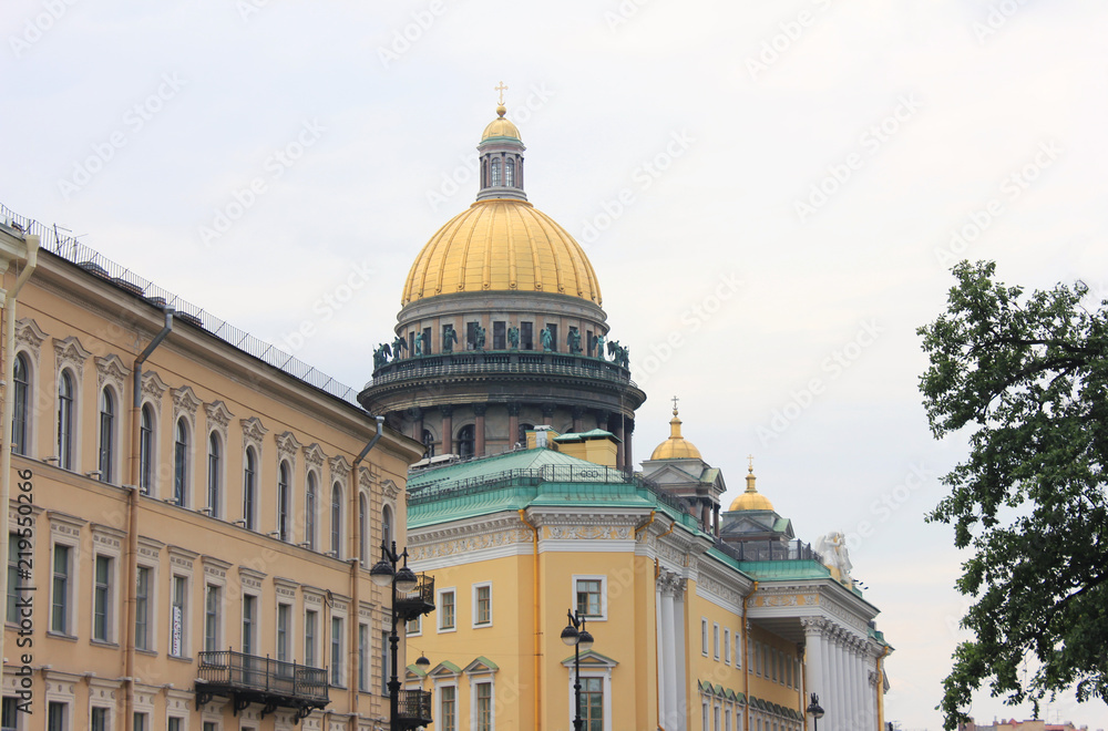 Saint Isaac's Cathedral Dome View from Behind a Classic House Building in St. Petersburg, Russia. Famous Russian Architecture, Cultural Travel Landmark Street View on Gloomy Day against Blue Sky.
