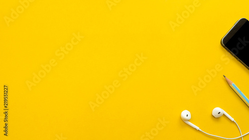 Earphone  with pencil and smartphone on yellow background  business concept copyspace