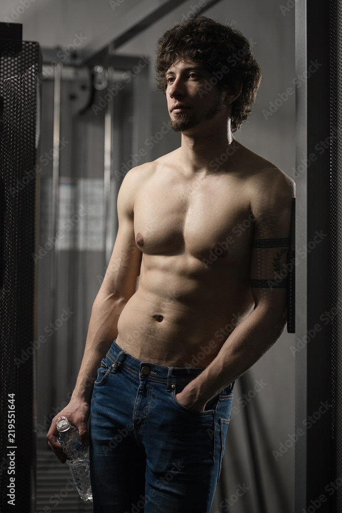 Young adult man standing with a bottle of water Young adult man standing with a bottle of water