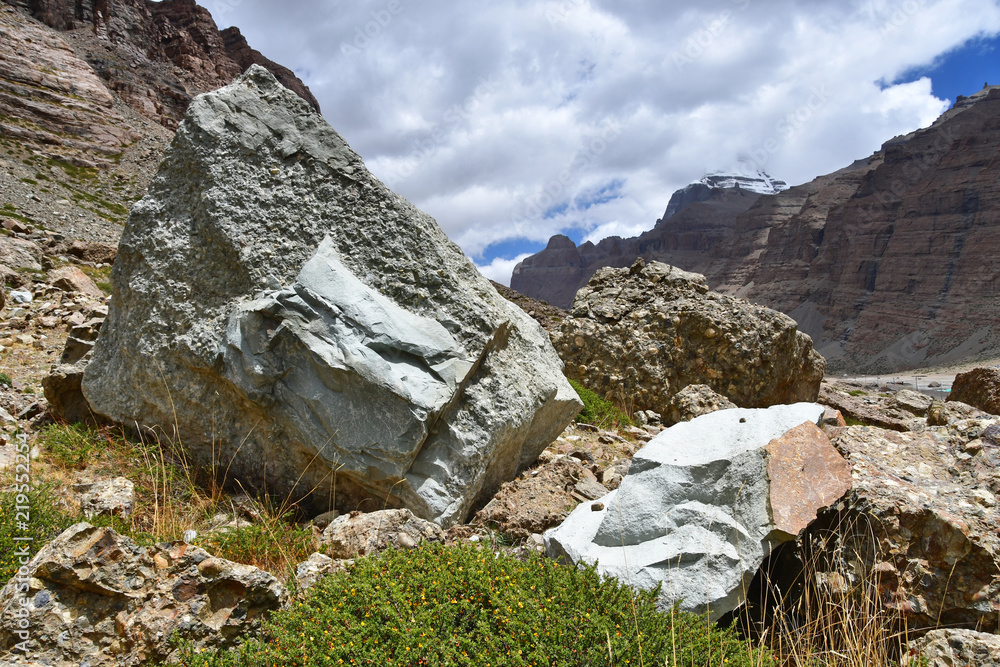 Каменные геоглифы с ликами на фоне южного лика горы Кайлас в облачную погоду