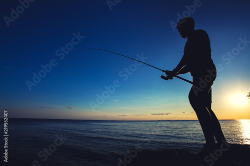 silhouette of a fisherman on the background of the setting sun