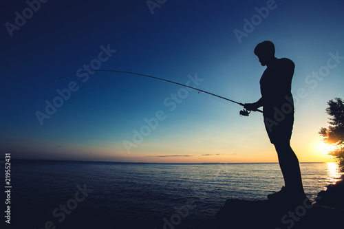 silhouette of a fisherman on the background of the setting sun