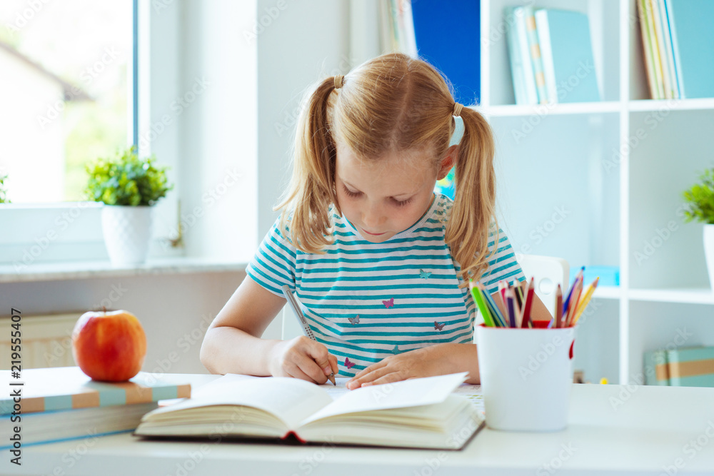 Portrait of schoolgirl at classroom writing at the table Portrait of schoolgirl at classroom writing at the table