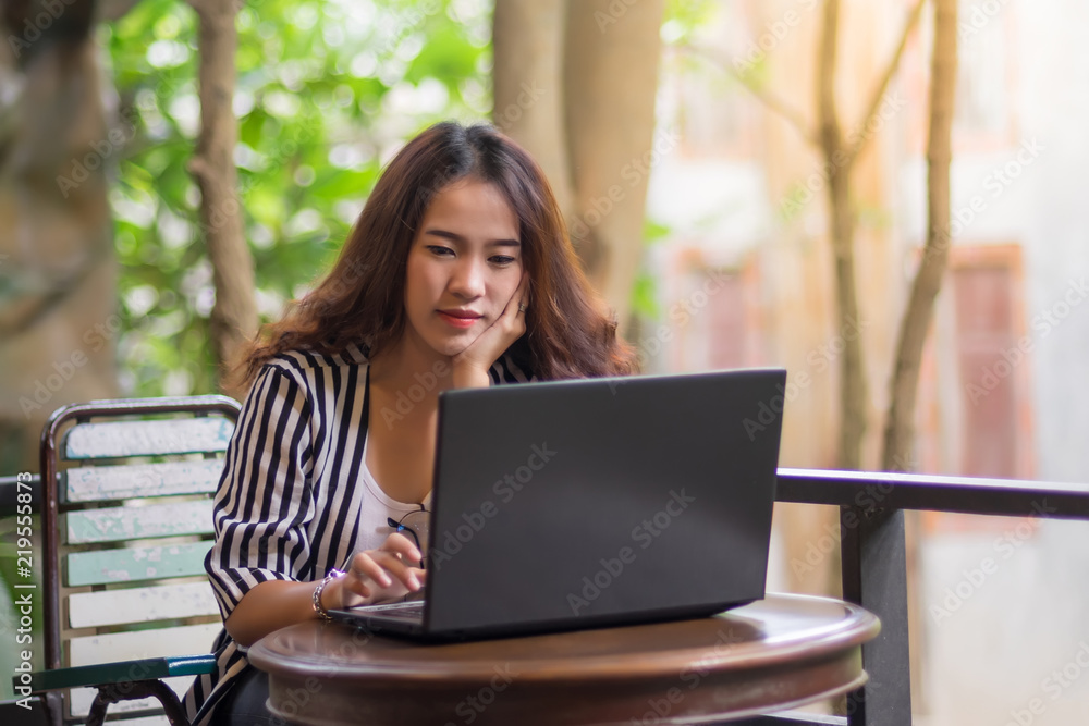 Young freelance woman using laptop to work outside coffee shop. Business person using laptop to communicate. Female student using laptop and study outside cafe in free time. Young freelance woman using laptop to work outside coffee shop. Business person using laptop to communicate. Female student using laptop and study outside cafe in free time.