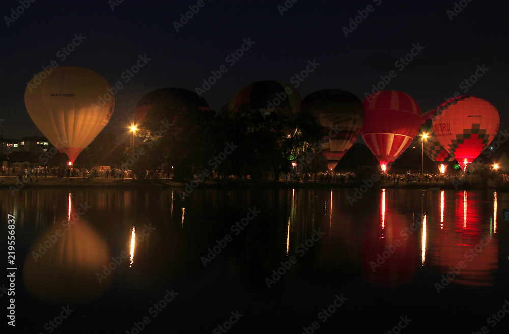 Fototapeta premium Hot air baloons flying in the evening sky near the lake