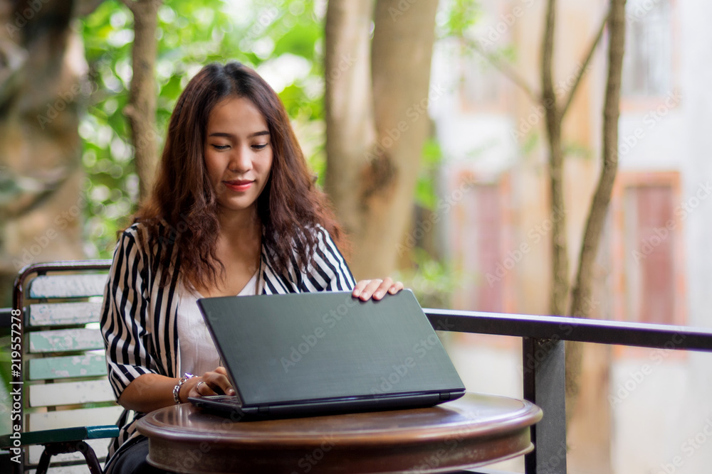 Young freelance woman using laptop to work outside coffee shop. Business person using laptop to communicate. Female student using laptop and study outside cafe in free time. Young freelance woman using laptop to work outside coffee shop. Business person using laptop to communicate. Female student using laptop and study outside cafe in free time.