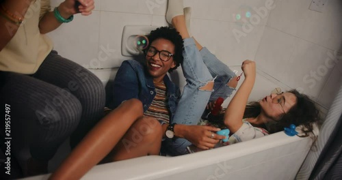 Happy teenage girls having fun blowing bubbles at slumber party photo