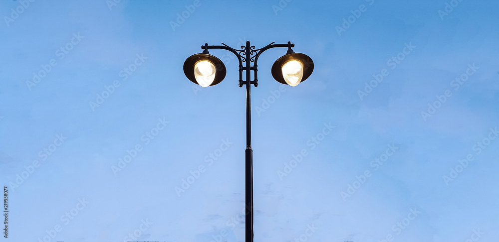 modern street lamp shines against a background of blue sky at sunset modern street lamp shines against a background of blue sky at sunset