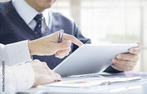 Businessmen or investors reviewing return on investment on a tablet mobile device. Side copy space included. photo