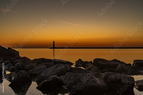 The entrance to a harbor with lighthouse at beautiful sunset photo