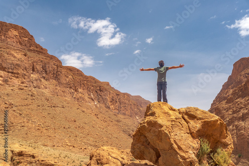 A man opening her arms, connected with the surroundings of the spectacular scenery in Morocco.