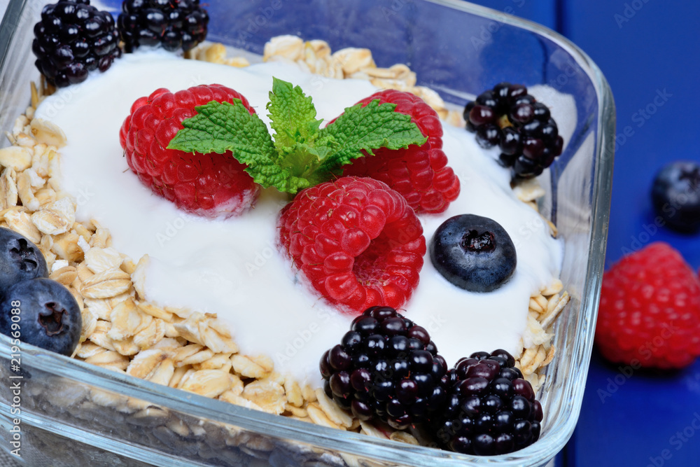 Granola with berries and yoghurt in a transparent bowl on wooden table Granola with berries and yoghurt in a transparent bowl on wooden table