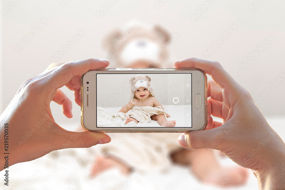 Woman photographing her baby with a cell phone. Photo camera of a smartphone.