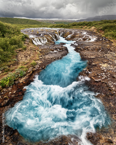Scenic view of a waterfall with blue coloring, in the background a mountain range - Location: Iceland, Golden circle