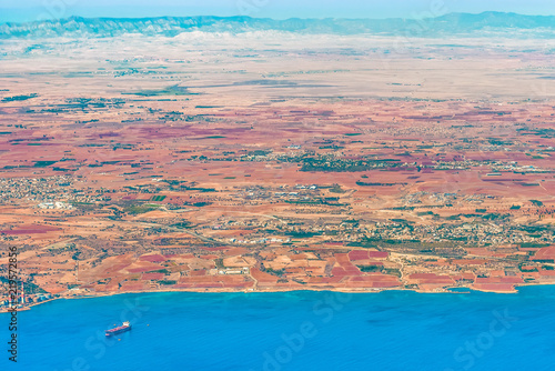 View of the island of Cyprus in the region of the bay of Dhekelia. Fragment of a power station, a sea dock, a villa and a village, a road and a mountain massif.