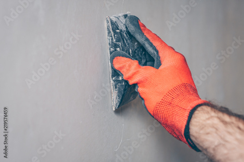 Foto The worker grinds the wall with sandpaper