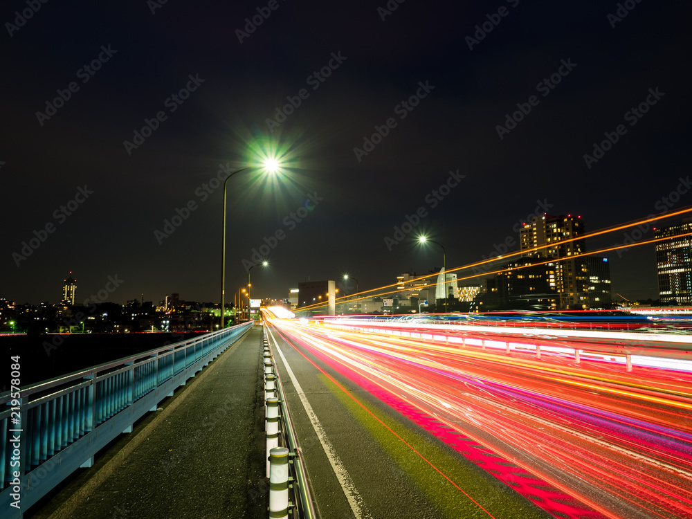 It is a scenery from the top of a bridge between Japan and Kanagawa Prefecture. The car's headlights and taillights are like laser beams.