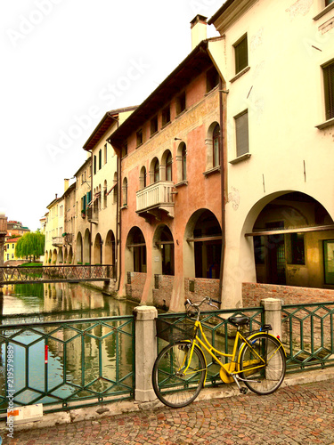 A bicycle rests upon railings of a bridge over a river in Treviso Italy